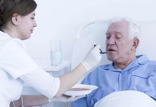 Personne au lit nourrie par une infirmière